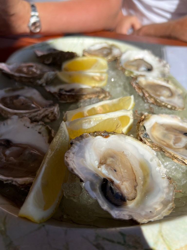 A plate of shucked oysters and wedges of lemons. 