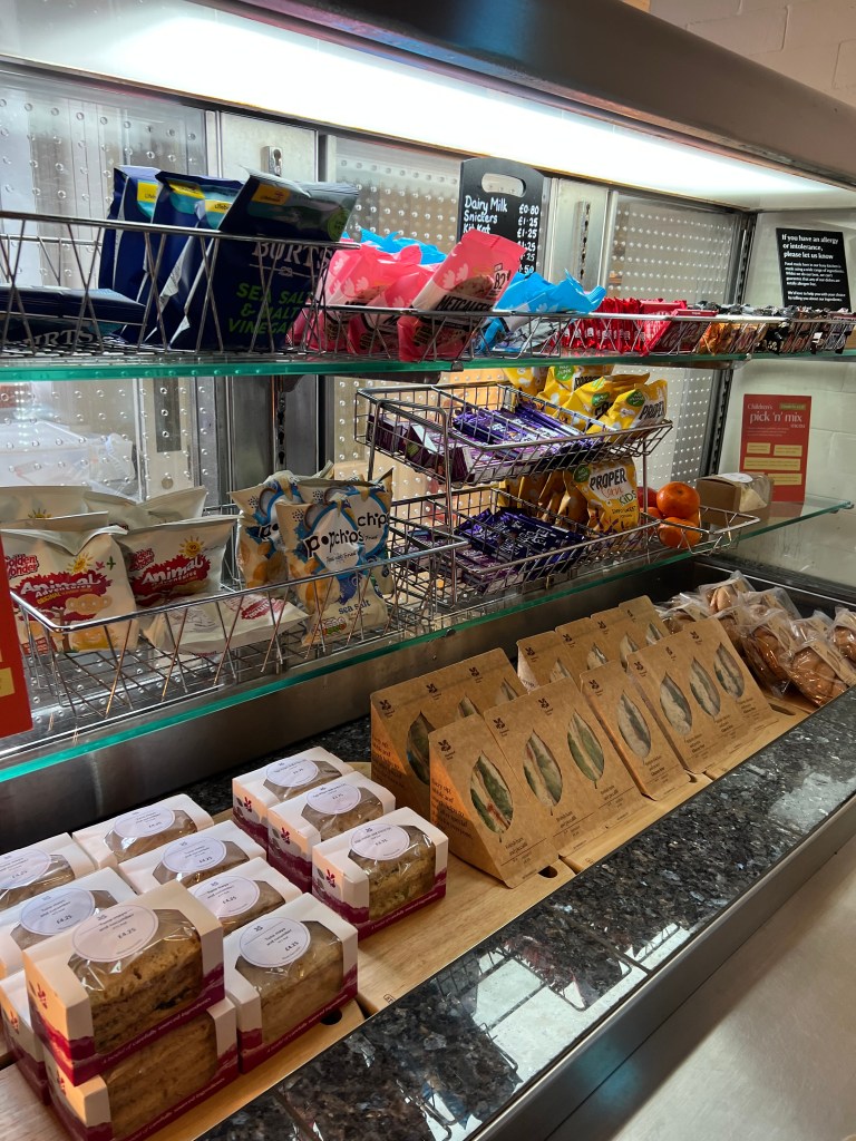 A refrigerated cabinet from the cafe containing sandwiches, crisps and snacks. 