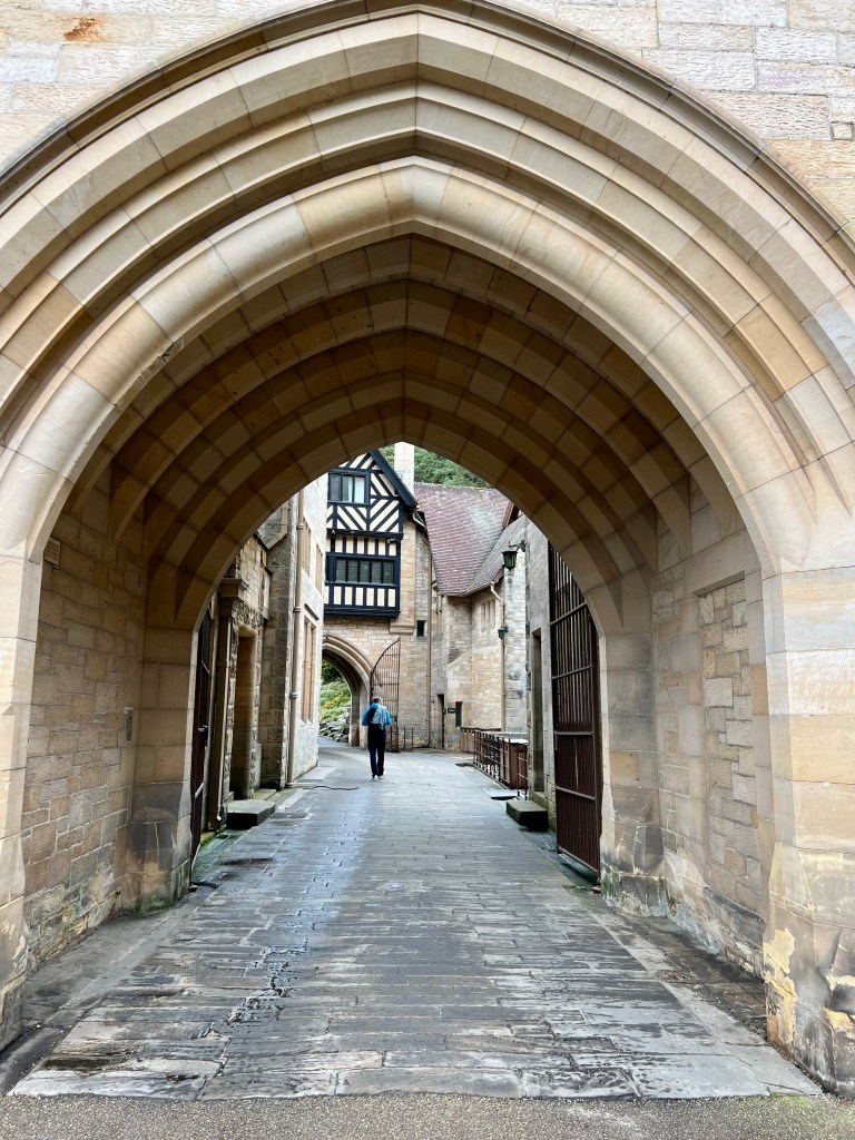 The carriage archway under Cragside house, a person wearing a blue jacket can be seen in the distance. 