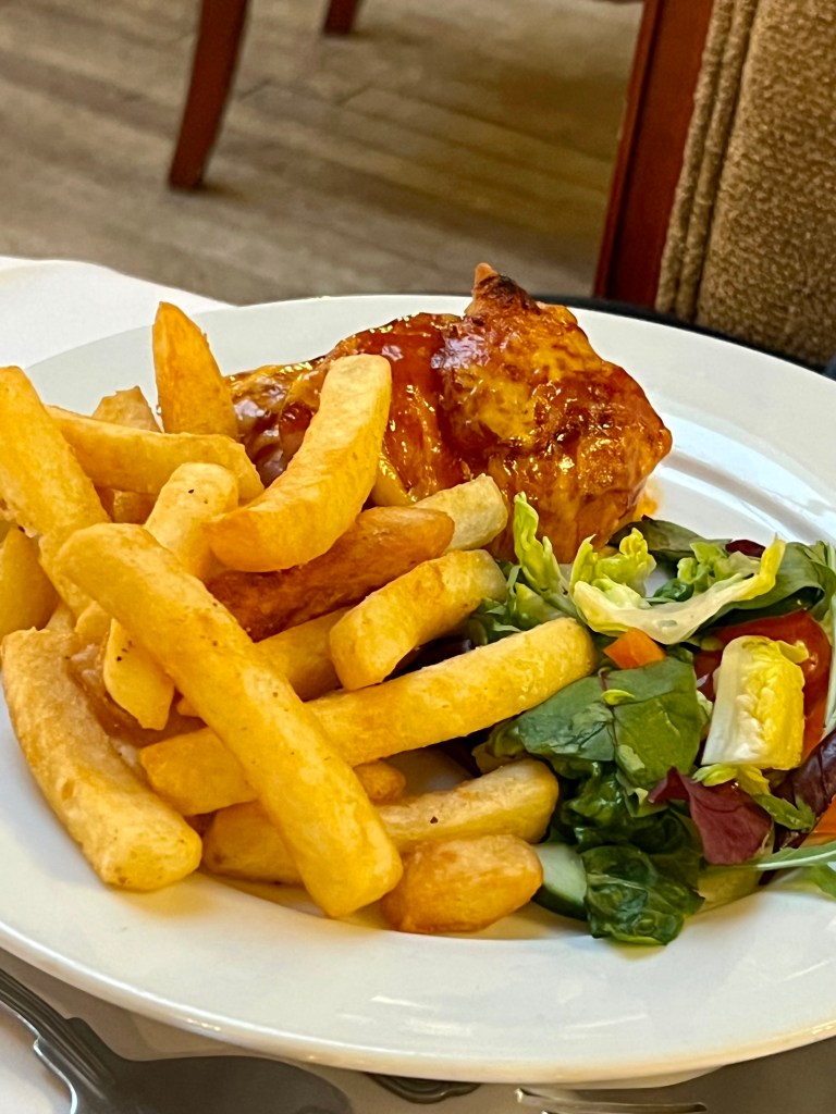 A plate of hunter's chicken with a serving of chips and salad.