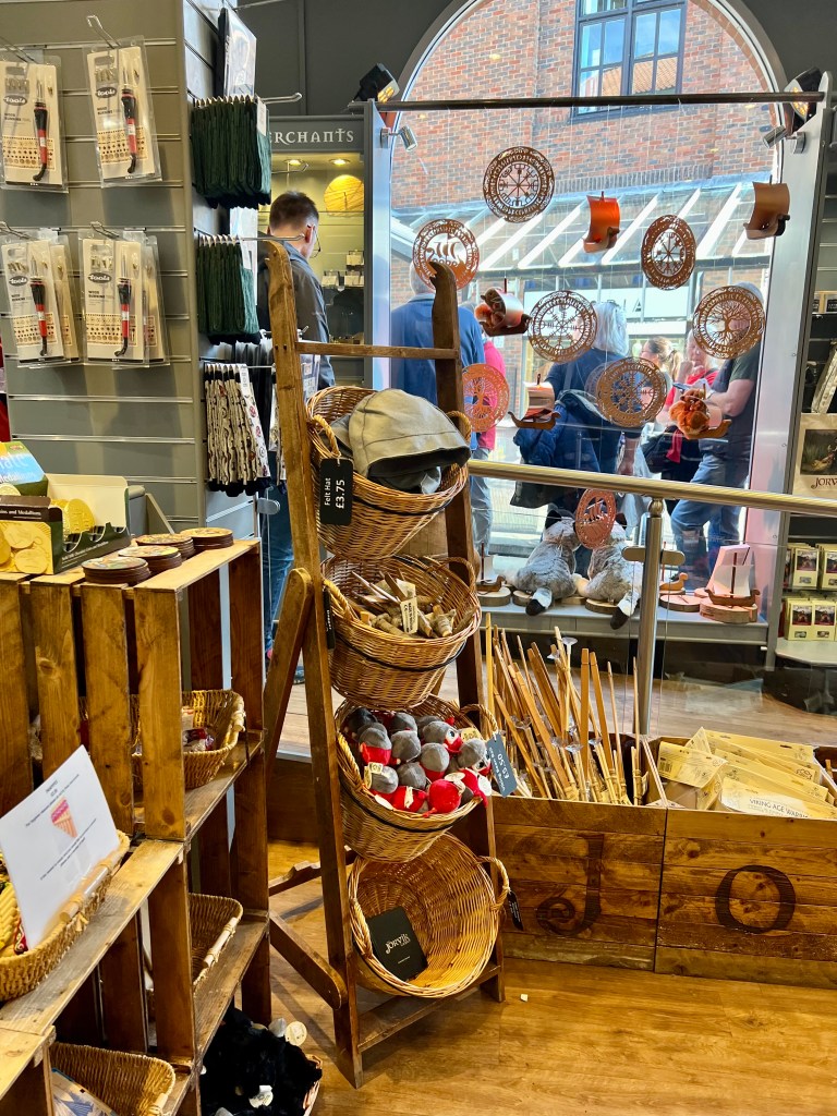 A photo of a display in the gift shop showing some wooden crates containing children's wooden bows and some round wicker basket shelves holding souvenirs. 