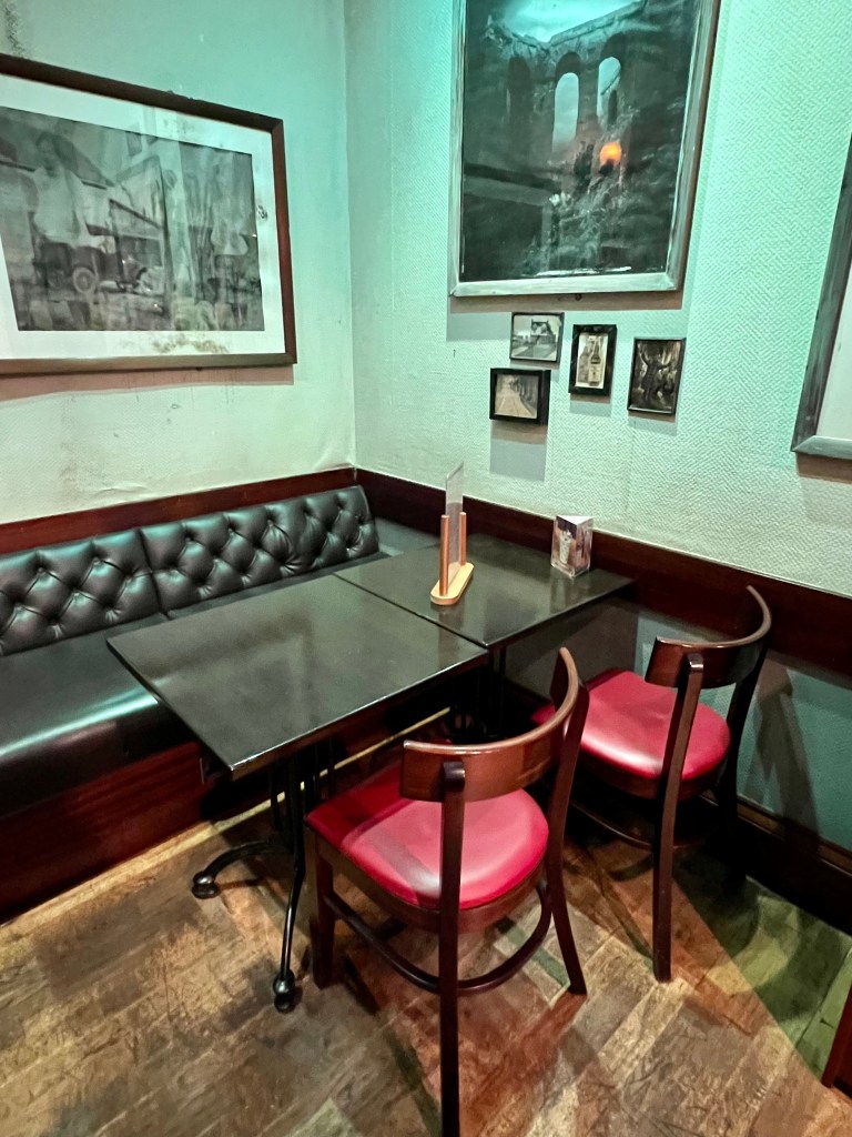 A black wooden table with  a black leather sofa seat at the back and two wooden chairs with red leather seats at the front. 