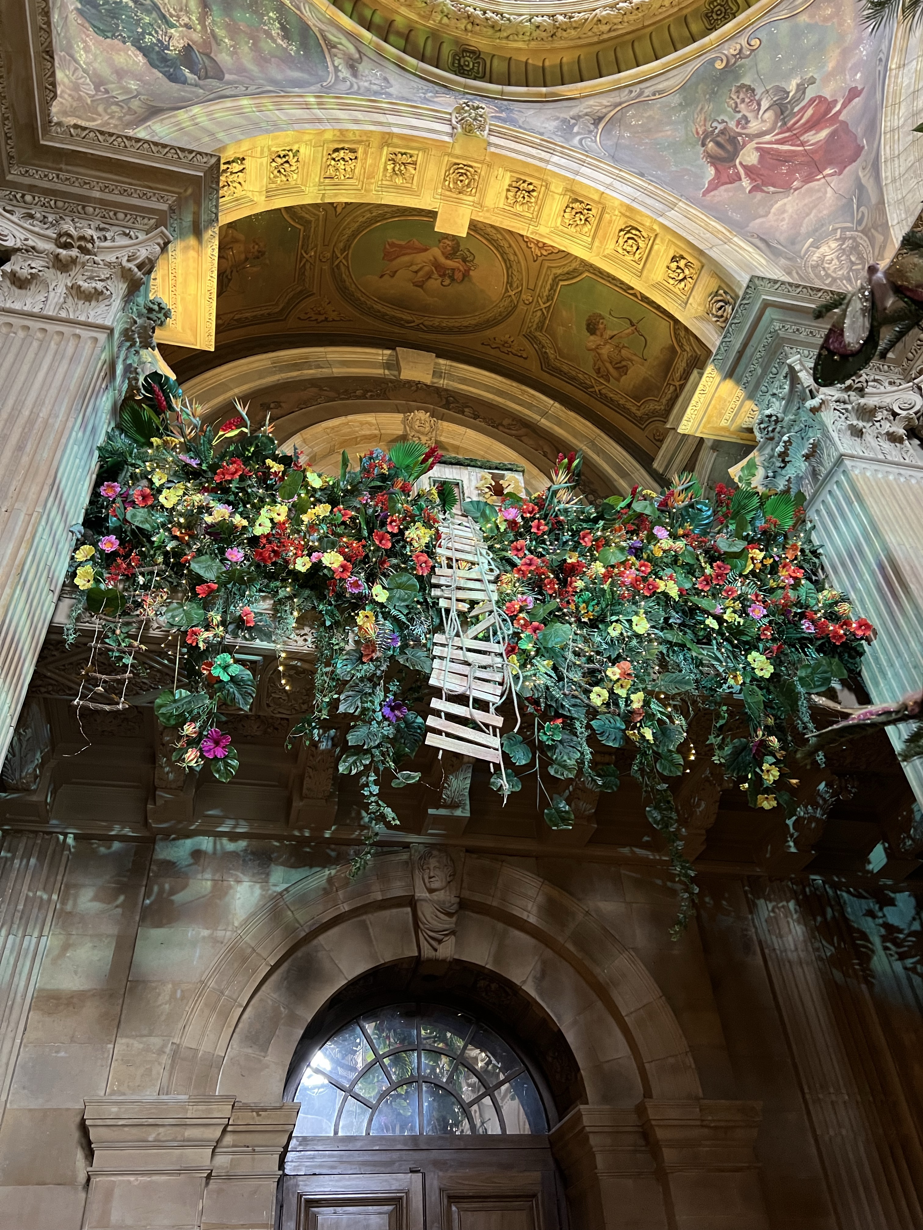 The balcony part of the main hall decorated with greenery and flowers. In the middle in a wood and rope ladder. The domed ceiling can be seen in the top of the photo. 