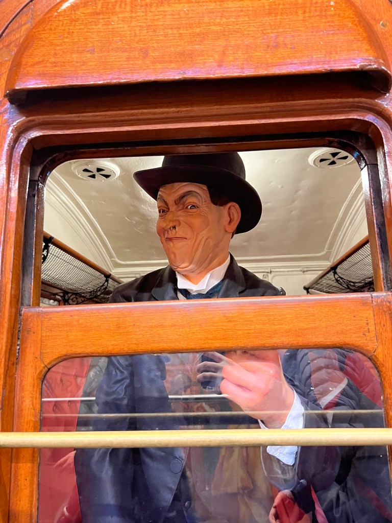 A mannikin of a passenger looks out of the open window or  subway door. 