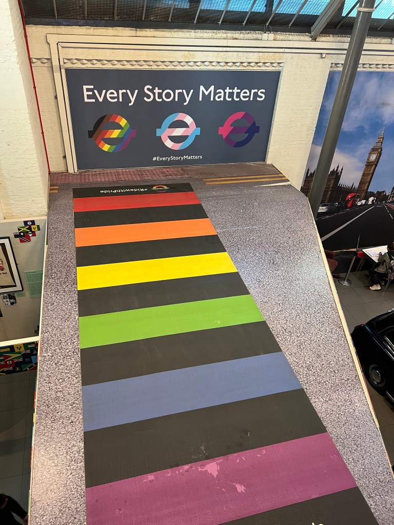 A rainbow crossing and an advertising poster with the words 'Every Story Matters' and 3 underground symbols in different pride flags. 