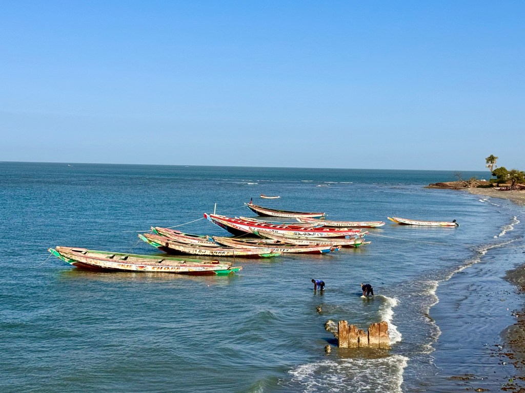 A line up of Senegalese fishing boats painted in bright colours at anchor in the sea. 