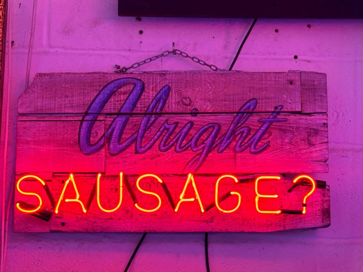 A neon sign that reads 'Alright Sausage'. 